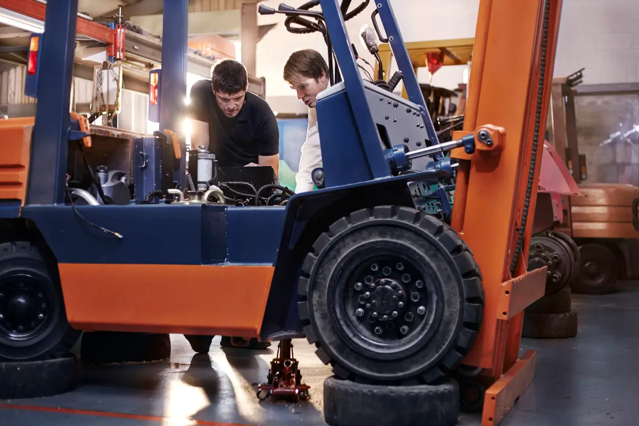 two mechanics are inspecting the forklift